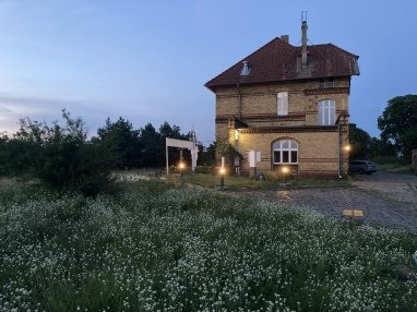Ansicht des Bahnhofs von der Einfahrt aus. Die Zeltwiese ist hinter dem Bahnhof